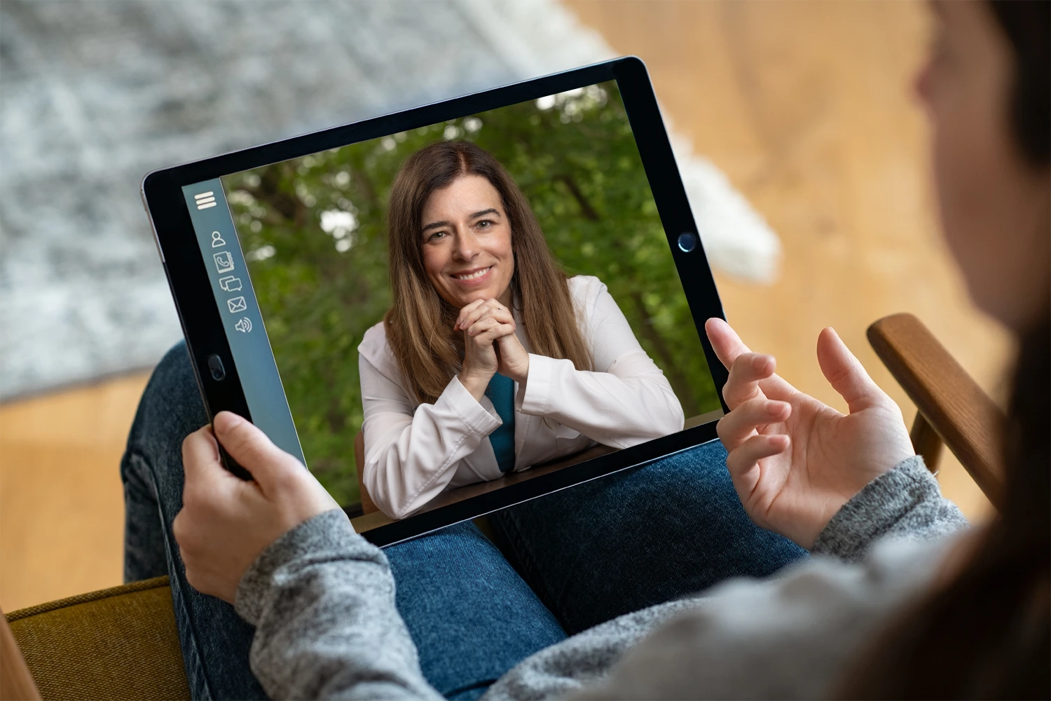 A person participates in a virtual consultation on a tablet with Dr. Amy Fogelman, MD, who is wearing a white coat and smiling warmly. Dr. Fogelman is a leading medical expert witness and founder of High Rock Experts, offering expert witness training and physician case reviews. This image represents remote expert witness consulting services for attorneys nationwide.